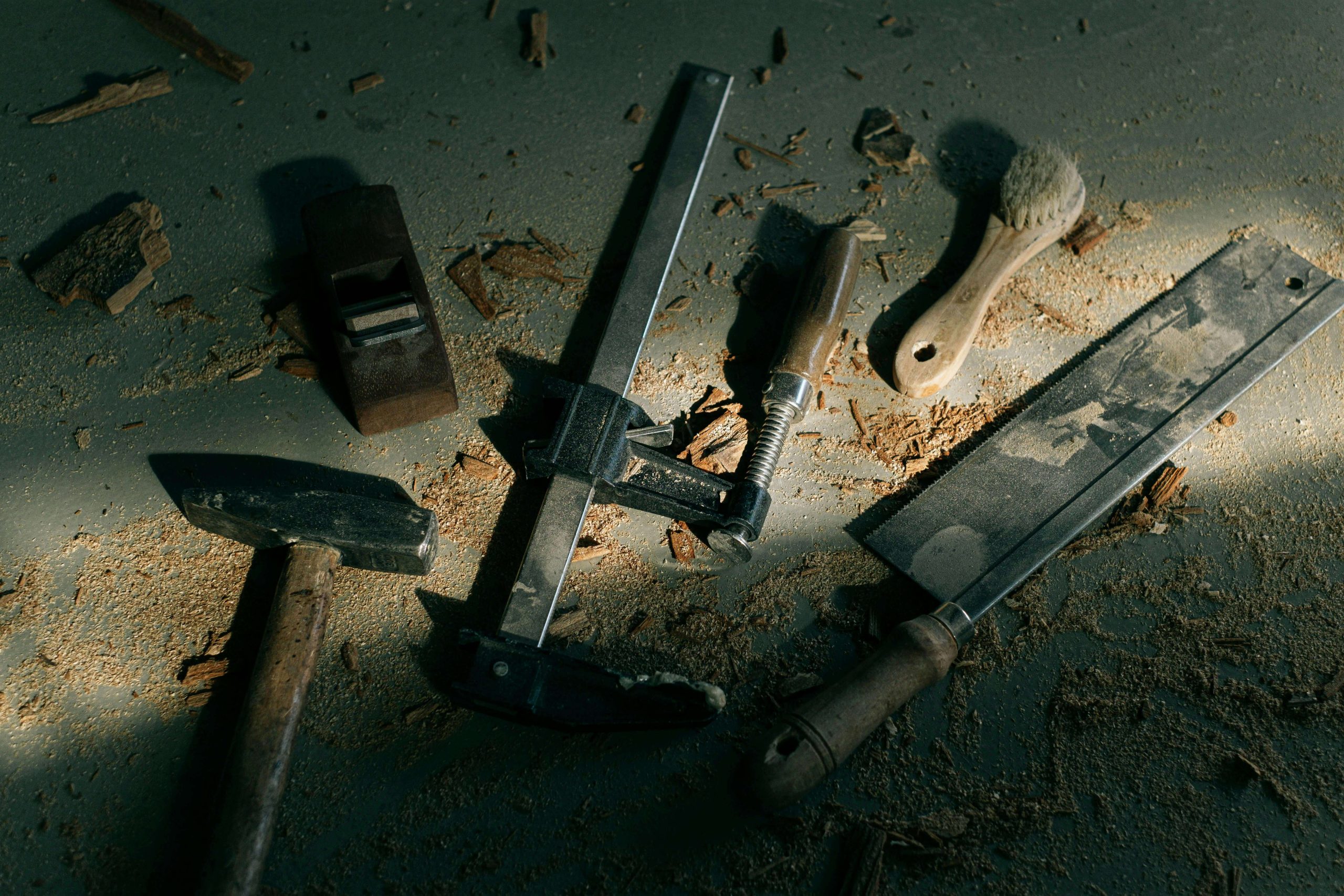 Assorted woodworking tools and sawdust scattered on a workshop floor.
