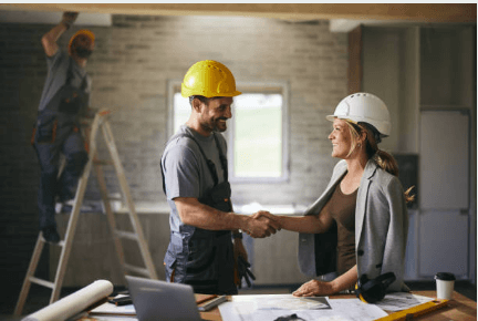 A contractor and business professional shaking hands on a construction site, symbolizing trust and partnership.